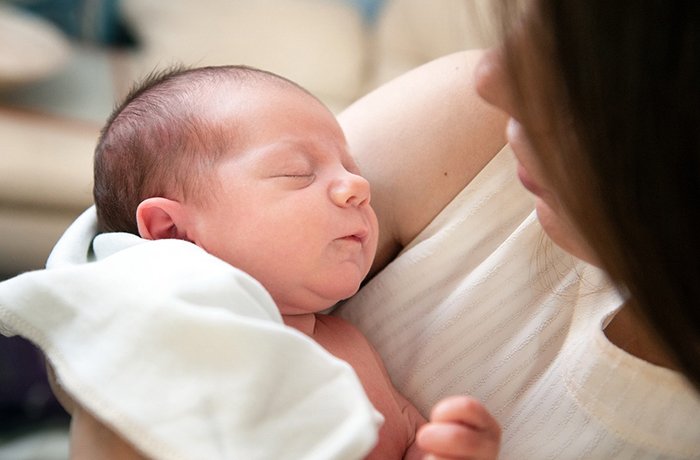 A mother swaddles her young baby